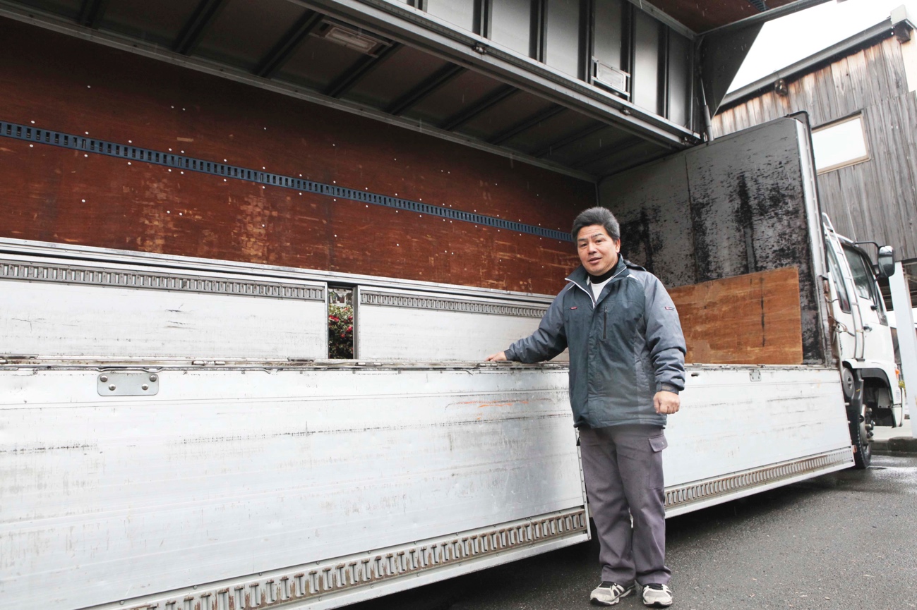 梱包した商品を運搬するため大型トラックの荷台に手を添える湯川さん
