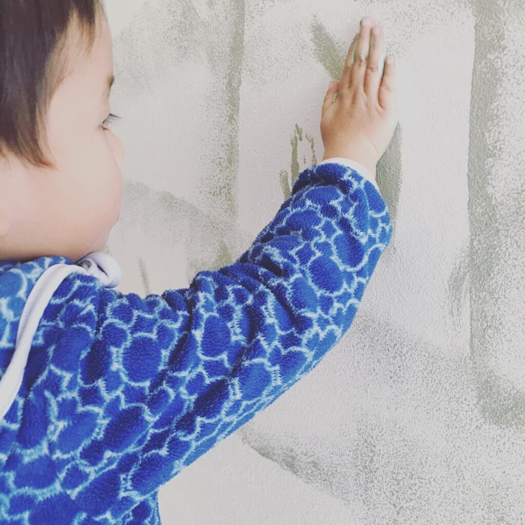 手でぺたぺたと壁を塗る子ども