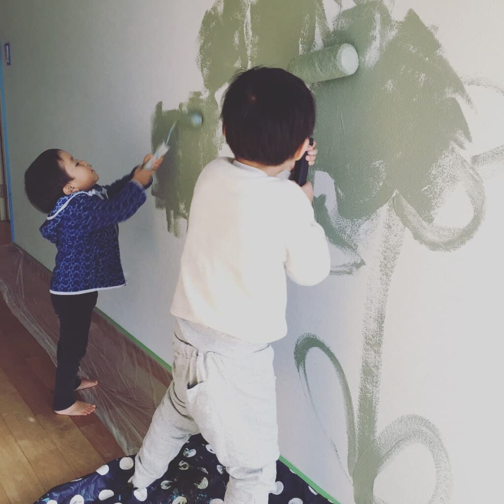 ローラーで一所懸命コロコロと壁を塗る子どもたち