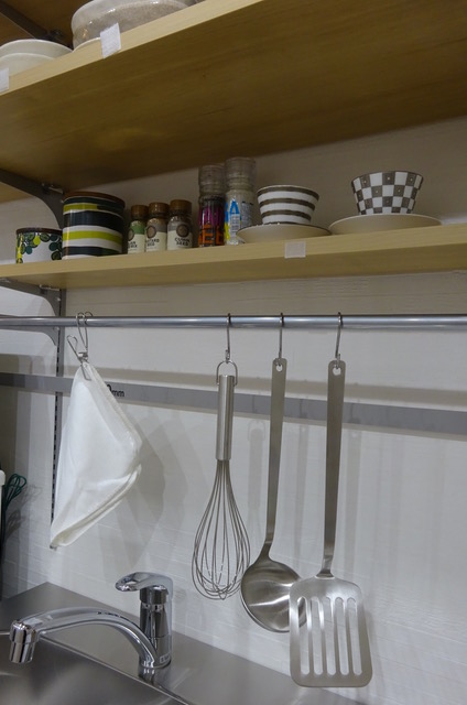 コンロ周りの棚や壁面に調理道具や調味料を収納したキッチン